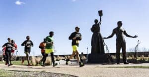 A group of people running in front of Richmond's Emancipation and Freedom Monument